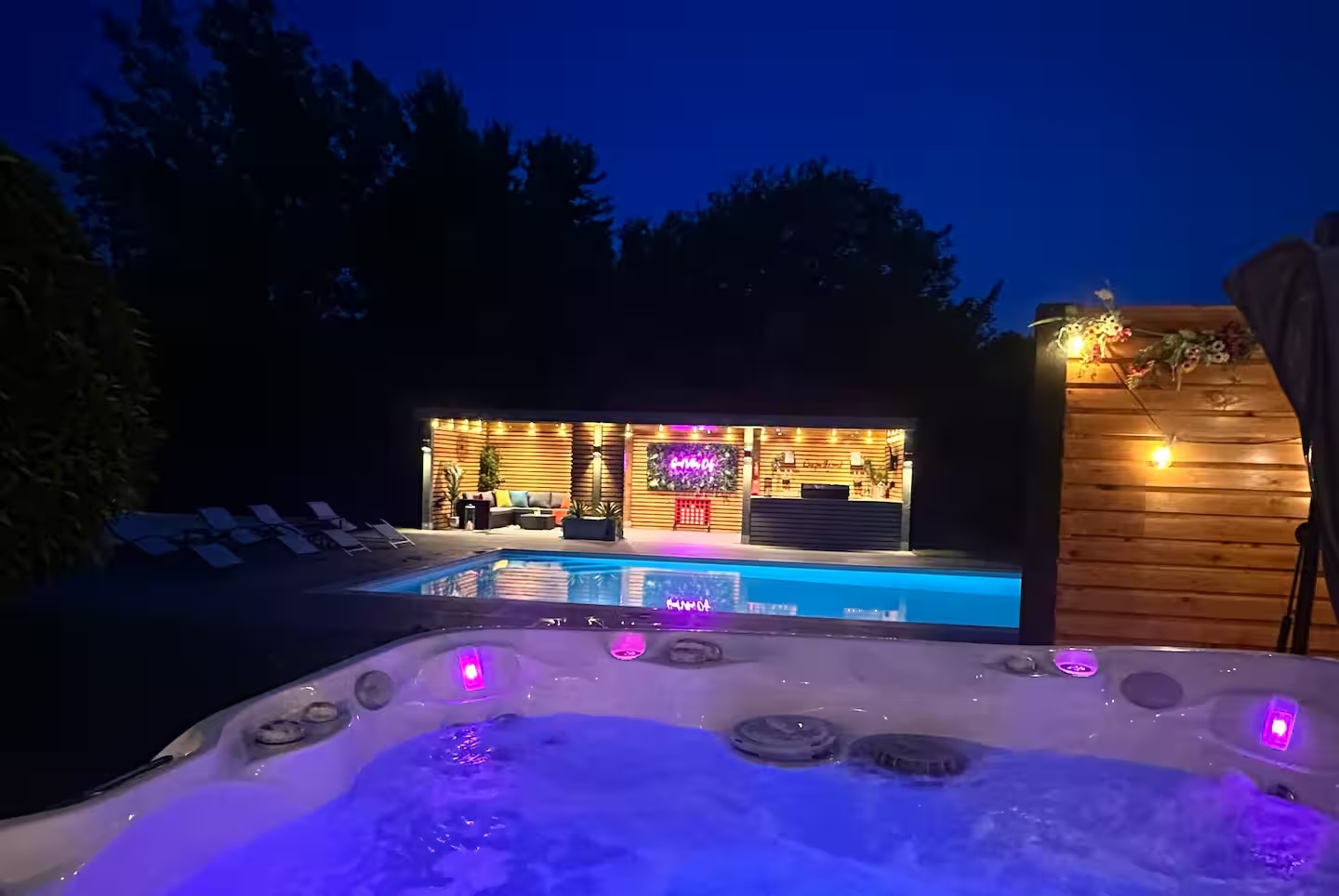 Night-time view from the bubbling hot tub across the pool